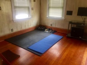 Photo of black mat on floor with weights nearby. Caption: "Guest room turned into exercise space."