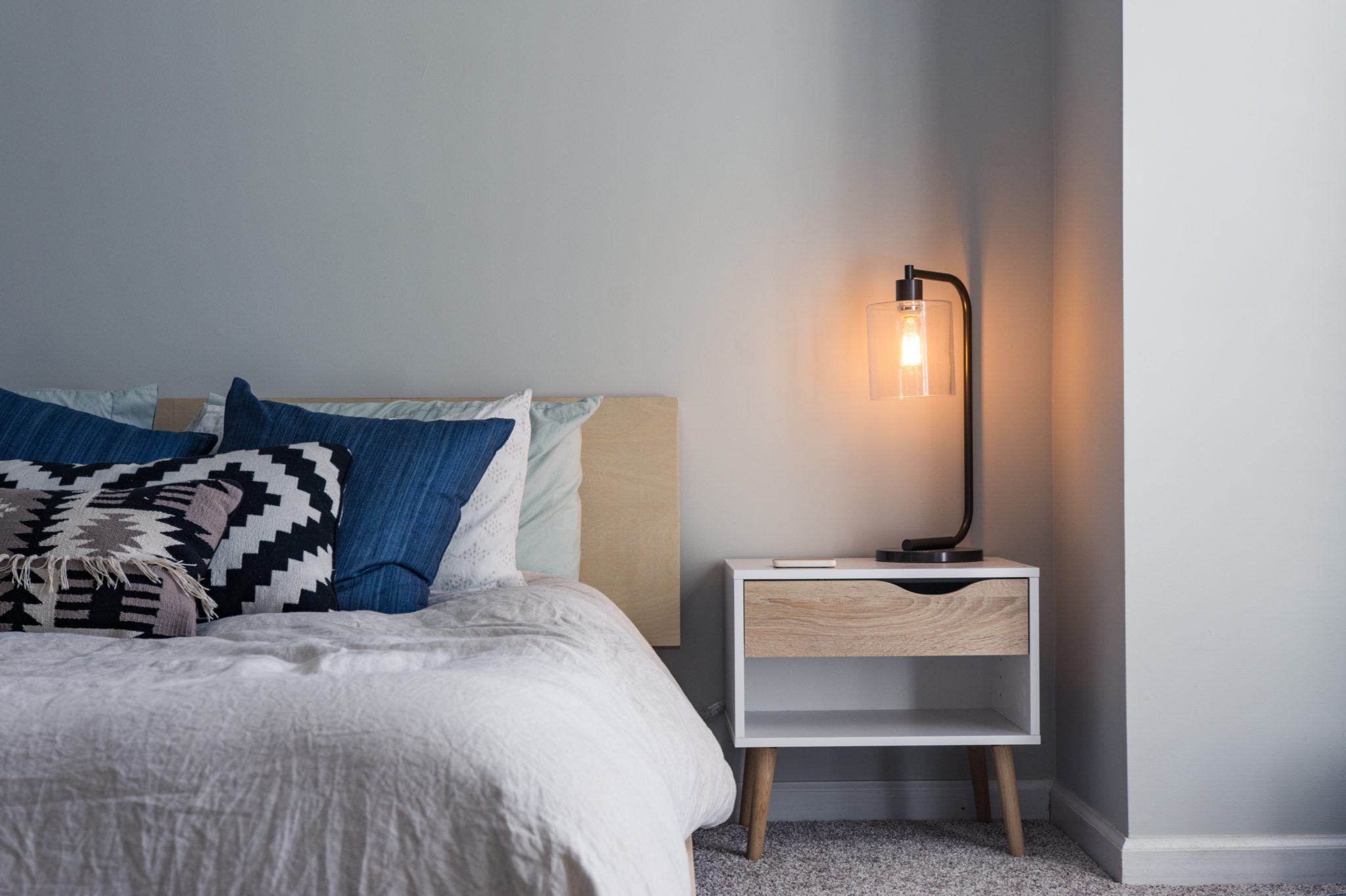 Photo of made bed and side table (Photo by Christopher Jolly on Unsplash)