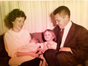 Henry and Erika Trapp, with daughter Barbara and newborn son Henry Joseph, sitting on sofa in 1962