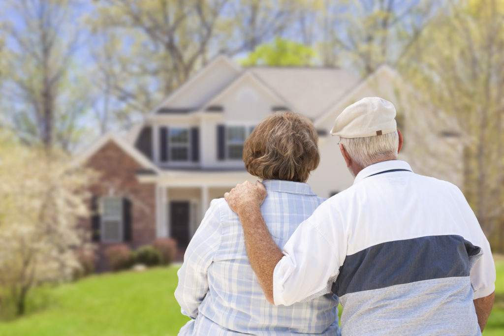 Elderly couple in front of two story house, with backs to camera